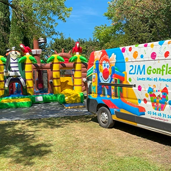 Camion coloré et château gonflable dans un parc.